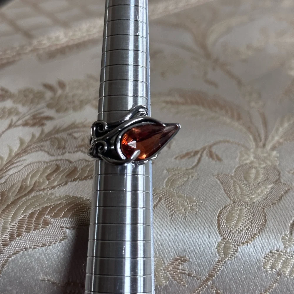 Ring in silver metal intricate with teardrop shaped amber color stone